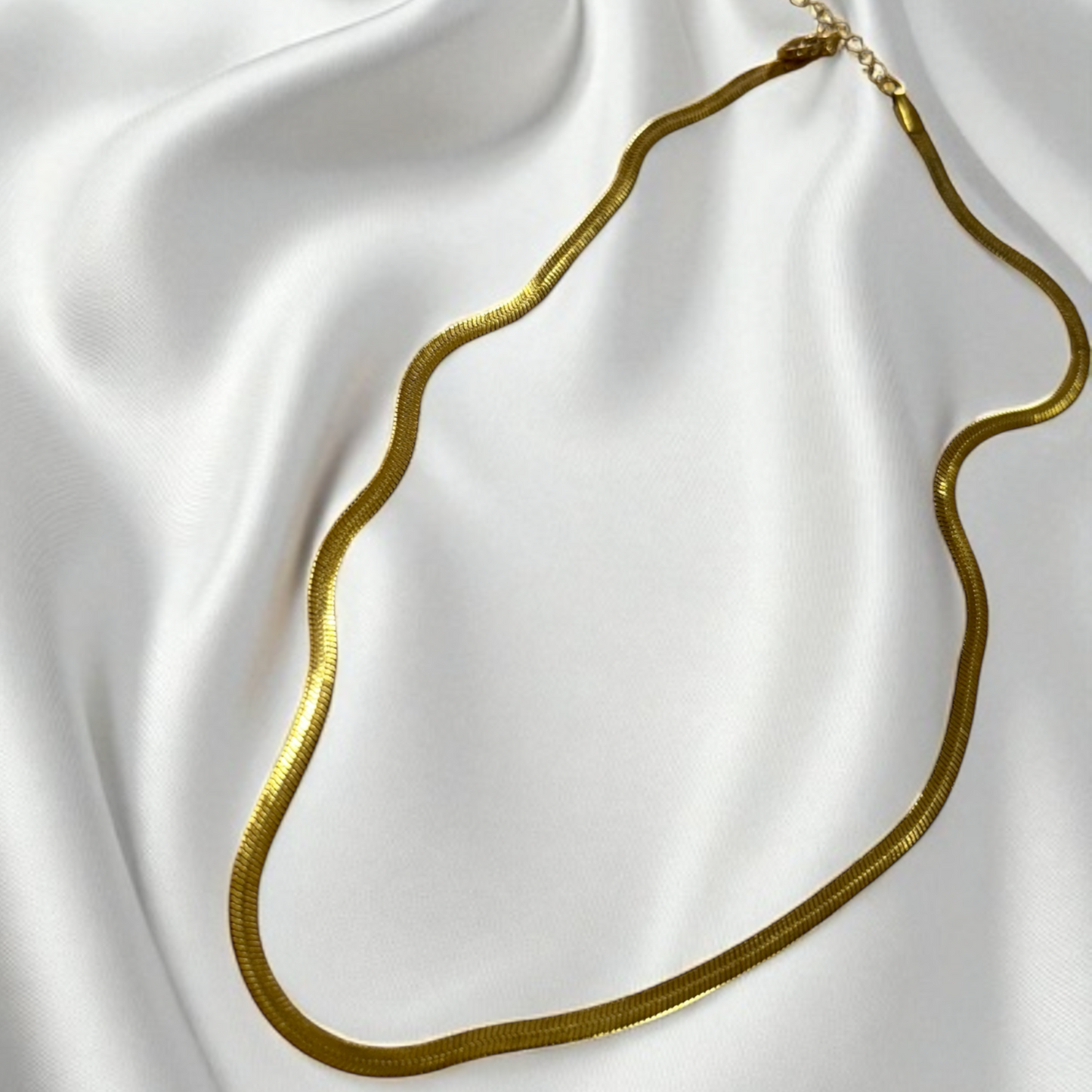 Gold necklace on a white satin background