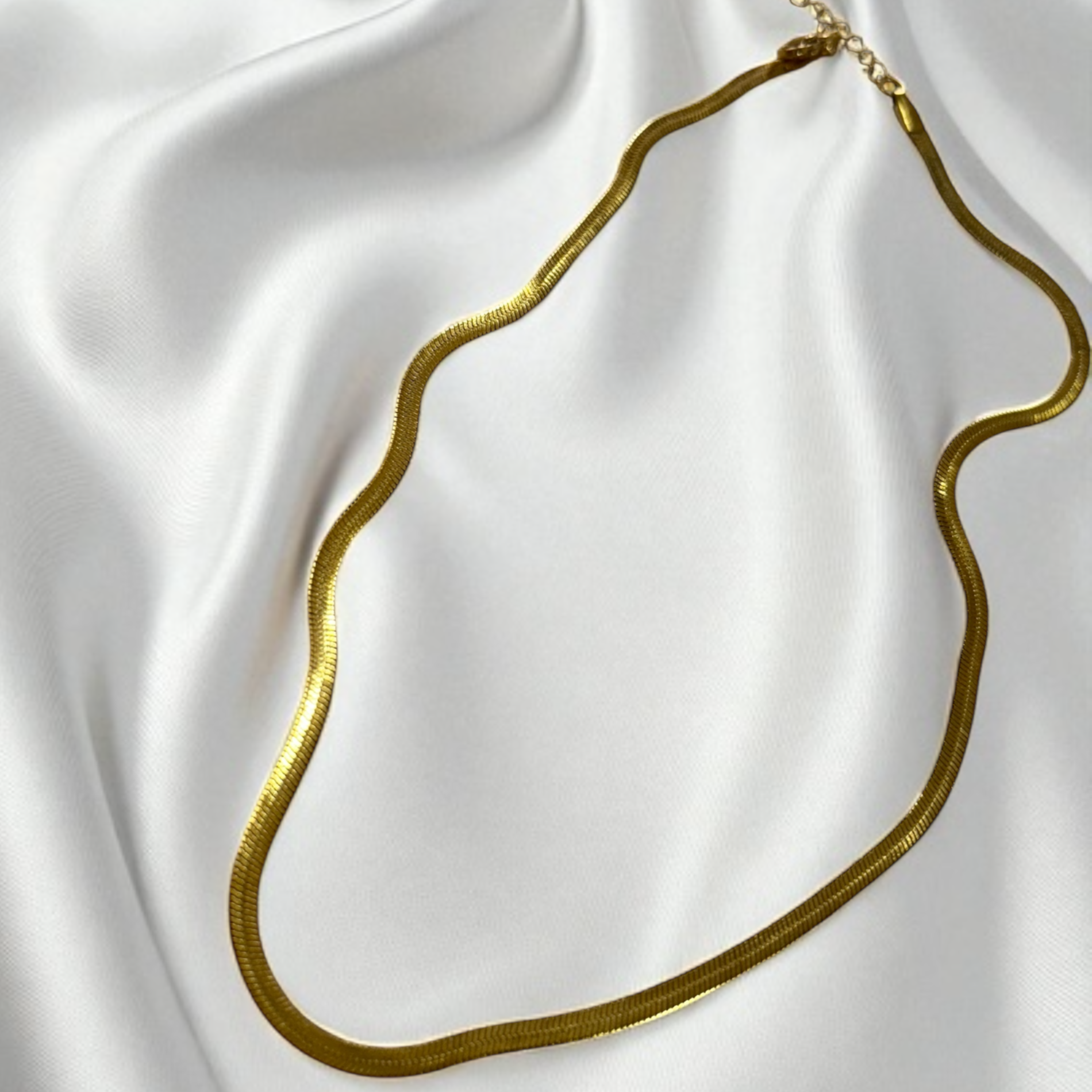 Gold necklace on a white satin background